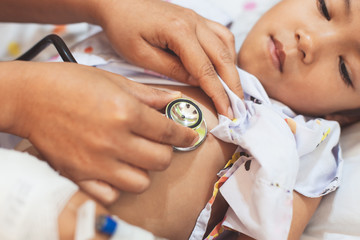 Doctor examining asian child girl and listen her lung and heart sound with stethoscope in the hospital