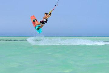 Kite surfing girl in sexy swimsuit with kite in sky on board in blue sea riding waves with water splash. Recreational activity, water sports, action, hobby and fun in summer time. Kiteboarding sport