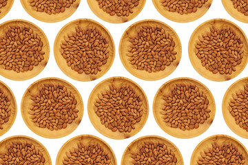 Peeled almonds  in a wooden pine plate on a white isolated background. Row of bowls with  almonds   nuts, top view. Peeled almonds   pattern