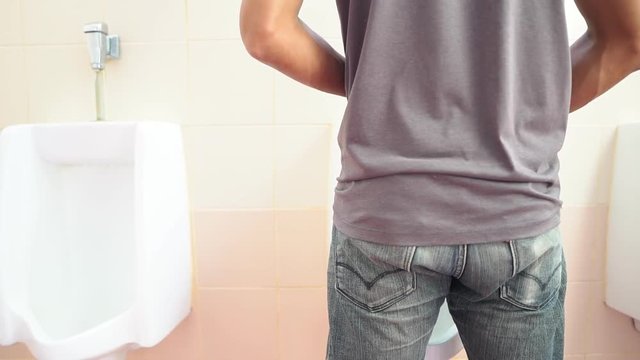The man went to urinate at the white jar in the toilet.