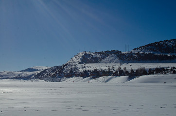 The cold frozen over lake in the bright winter sun of the utah mountains. 