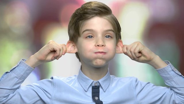 Pre-teen boy making monkey face. Close up child grimacing on abstract blurred background. Kid fooling around.