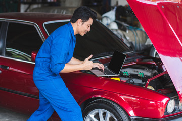Professional mechanic working in auto repair service,with laptop,very good engine
