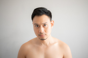 Serious and stress face of Asian man in topless portrait isolated on gray background.