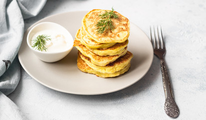 Zucchini fritters served with fresh herbs and yogurt dressing. Vegetarian zucchini pancakes. Copy space.
