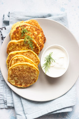 Zucchini fritters served with fresh herbs and yogurt dressing. Vegetarian zucchini pancakes. Copy space.