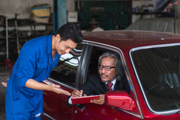 Fototapeta na wymiar auto service, repair, maintenance concept mechanic with clipboard and car owner businessman checking repair items car