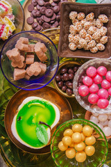 Tea break with a delicious honey cake decorated in the form of a green apple and a variety of multi-colored small candies. Copper and clay plates in a composition with jugs. Arab concept