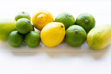 Ripe lemons and limes on white wooden.
