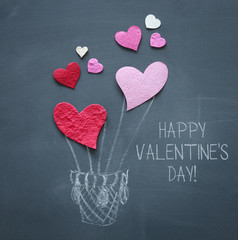 Valentine's day concept. pink and red paper hearts as air balloon over blackboard.