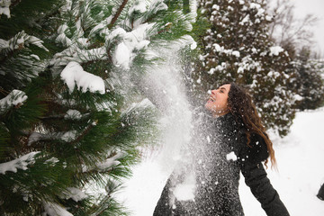 A beautiful pregnant woman is playing outside in the snow