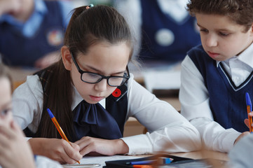 Naklejka na ściany i meble Schoolchildren sit at their desks in the classroom during school hours.