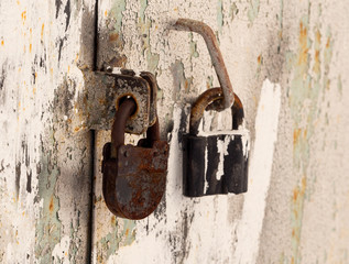 The metal door is closed by an old lock. The second spare lock weighs on the entrance handle. Old locks on the door.