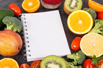 Notepad and fruits with vegetables containing natural vitamins and minerals, slimming and diet concept