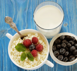 Cottage cheese with berries, waffles and milk on a wooden blue background. Top view.