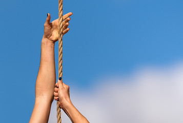 Athletic woman working out and climbing a rope, during obstacle course in boot camp