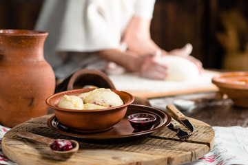 Ukrainian dumplings on a wooden board on the background of the hands of a baker
