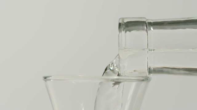 SLOW MOTION: Pouring vodka from a bottle into a glass - Macro, Side view