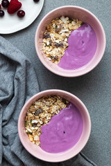 Bowl of oat granola with yogurt, fresh raspberries, cranberries