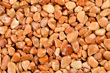 Extreme close up natural stone carpet, coloured in different shades and tints of sandy brown and beige. Decorative stone coating. Slip resistant floor finish containing natural stone particles.