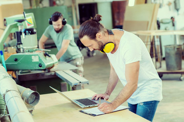 worker in a carpenter's workshop with computer and clipboard © Firma V