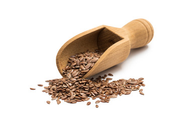 Linseeds or flax seeds on a wooden scoop or spoon from the front isolated on white background