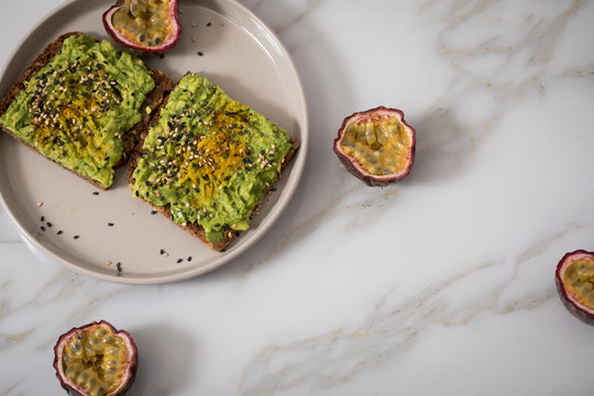 Avocado Kurkuma Vollkorn Sonnenblumenkern Brot und Maracuja zum Frühstück auf Marmor Hintergrund