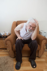 Old sick lonely man in the armchair at home