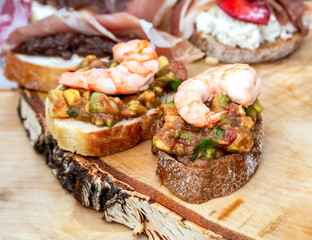Sandwiches with shrimps and fresh vegetables on wooden board