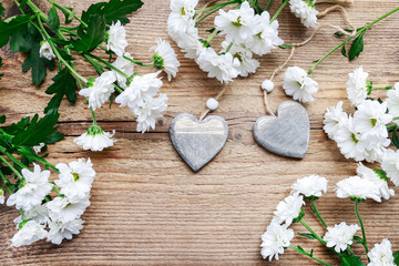 Wooden hearts among white chrysanthemum flowers.