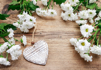 Wooden heart among white chrysanthemum flowers