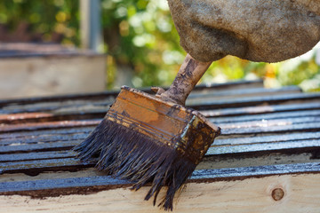 Male worker in old glove is painting boards for home decoration