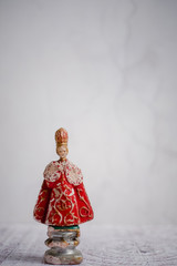 Antique statue of the Infant Jesus of Prague, against a light background. 