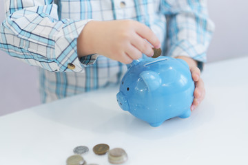 three years old boy puts money in a piggy bank, piggybank concept. mantesori space in the house