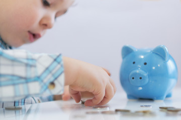 three years old boy puts money in a piggy bank, piggybank concept. mantesori space in the house