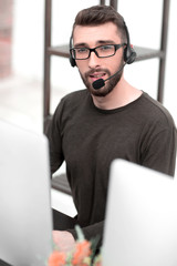 close up.a modern man in a headset works on a laptop.