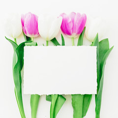 Floral composition of tulips flowers and paper card with copy space on white background. Flat lay, Top view.