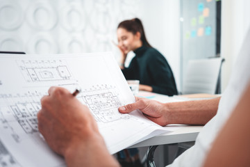 Two architect design concept blueprint. Young man and woman designer sketching a construction project at laptop and drawing plan while working at office