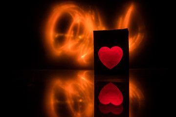 Blurred neon heart icon on a dark background. Copy space with red bright colorful heart on black background