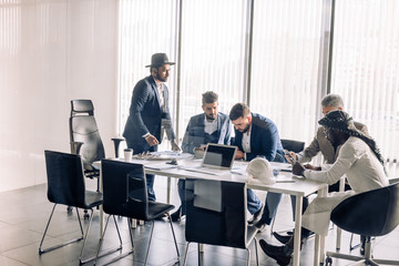 Serious Indian CEO in interacting with multiracial vendors at corporate meeting, explaining development project strategy, proving them to continue cooperation.