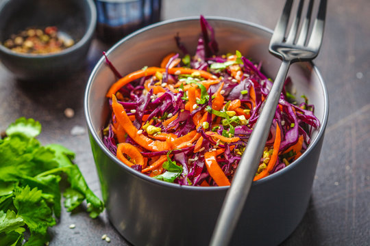 Coleslaw in a gray bowl on dark background. Red cabbage and carrot salad.