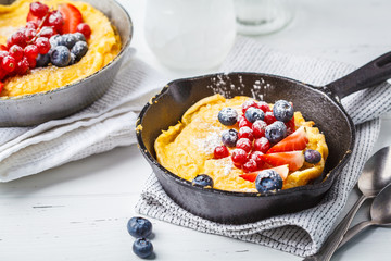 Dutch baby pancake with berries in a cast-iron pan.