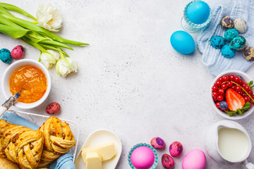 Easter Breakfast table, top view. Colored eggs, flowers, buns, milk, juice and jam, white background.