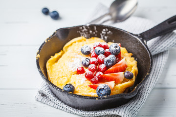 Dutch baby pancake with berries in a cast-iron pan.