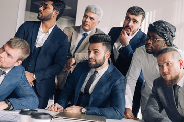 Formal meeting of several multi-ethnic male colleagues gathered in executive s office to discuss new ideas