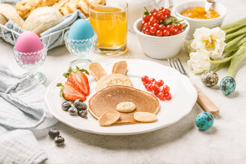 Easter bunny of pancakes with berries. Easter Breakfast table. Colored eggs, milk, juice and jam.