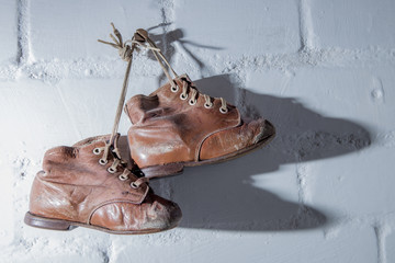 old, worn children's shoes hang on a wall