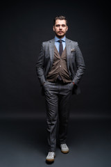 Fototapeta premium Full length portrait of a fashion male model over black background. Looking at camera.