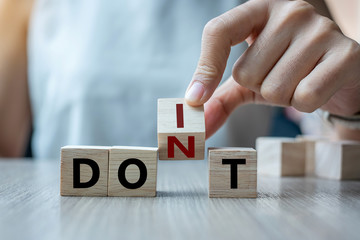 Businesswoman hand holding wooden cube with flip over block DON T to DO IT word on table background. success, strategy, solution, business and Positive thinking concepts