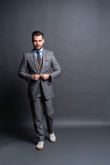 Full length portrait of a fashion male model over grey background. Looking at camera.